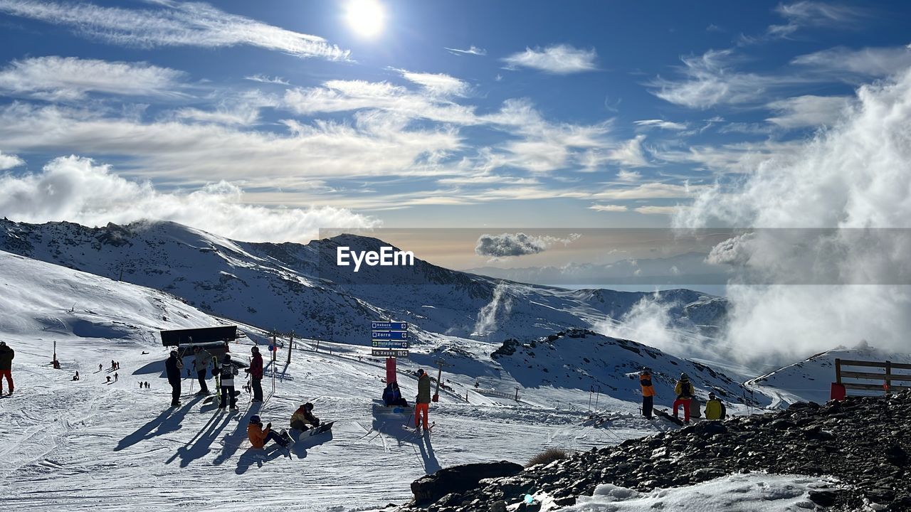 mountain, snow, cold temperature, winter, sports, sky, mountain range, scenics - nature, winter sports, beauty in nature, nature, environment, leisure activity, landscape, vacation, adventure, skiing, snowcapped mountain, group of people, trip, travel, cloud, holiday, travel destinations, sunlight, day, non-urban scene, ski equipment, ski holiday, ski, activity, motion, extreme sports, large group of people, outdoors, lifestyles, sun, tourism, land, white, men, ski mountaineering, tourist, sports equipment, recreation, crowd, piste, adult, ski resort
