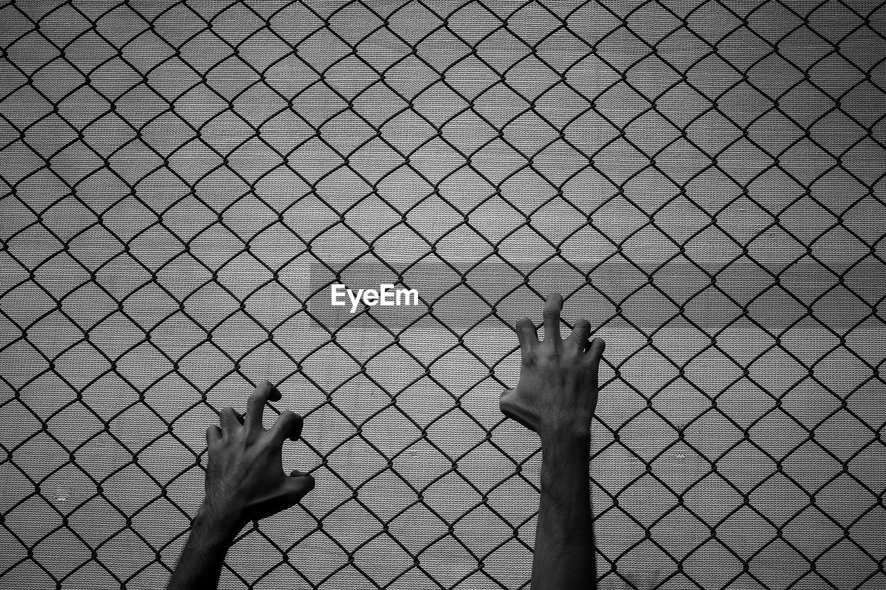 CLOSE-UP OF HUMAN HAND ON FENCE