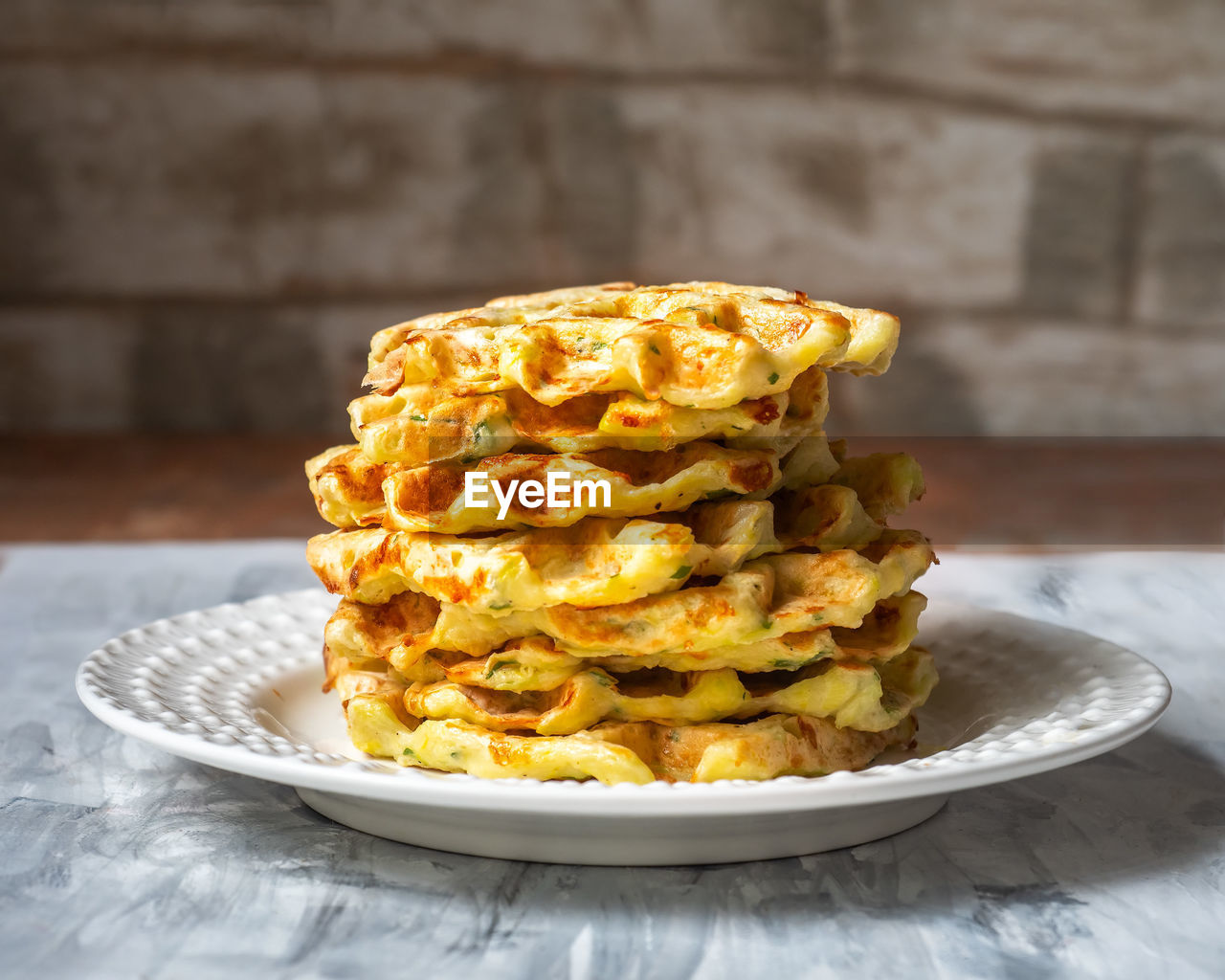 Stack of vegetable waffles on white plate in rustic kitchen close up