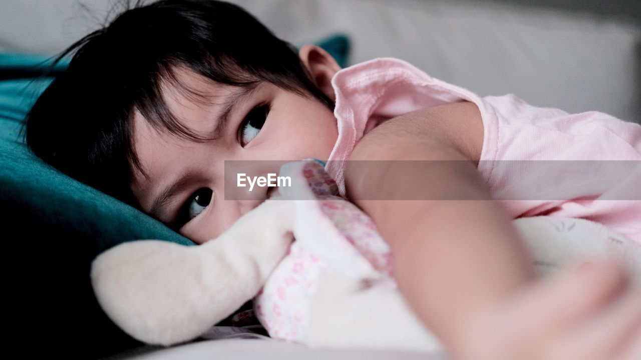 Close-up of baby girl lying on bed at home