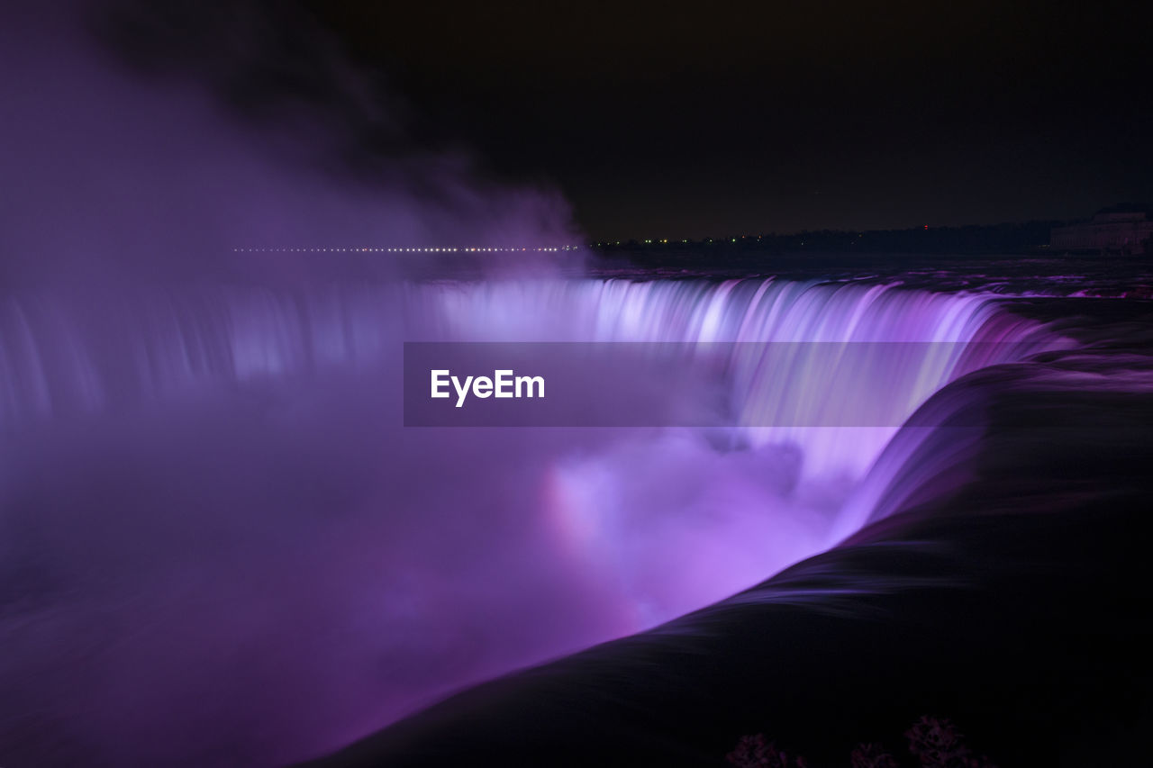 IDYLLIC VIEW OF WATERFALL AGAINST SKY AT NIGHT