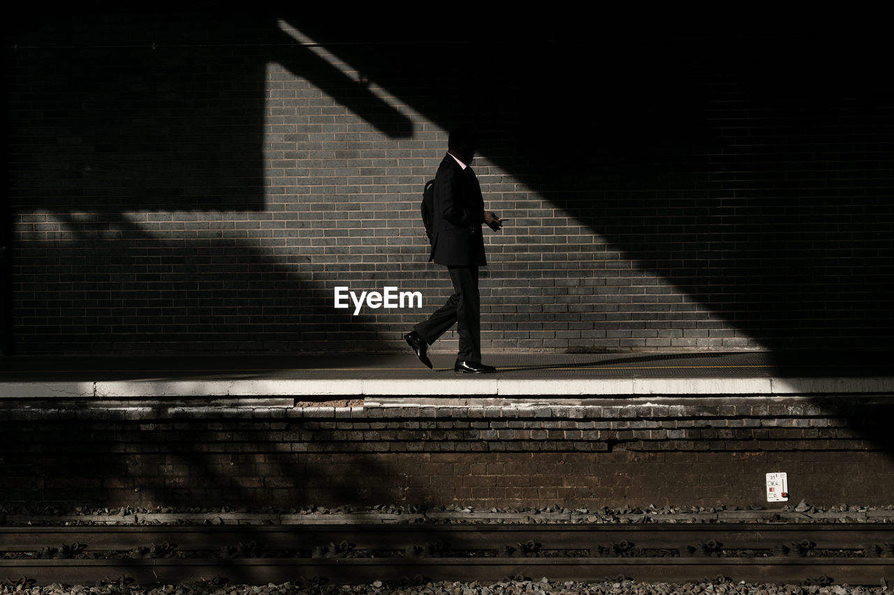 Side view of man walking on railroad station platform