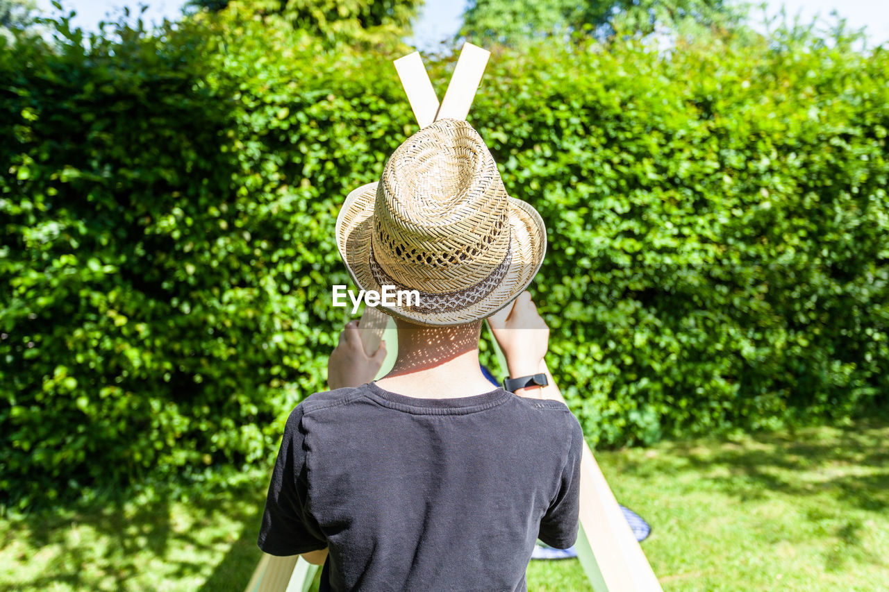 Rear view of boy wearing hat at backyard