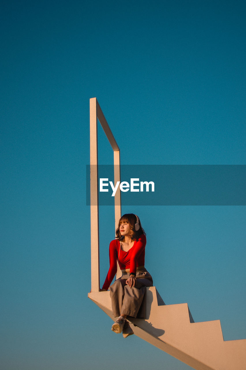 PORTRAIT OF WOMAN AGAINST BLUE BACKGROUND