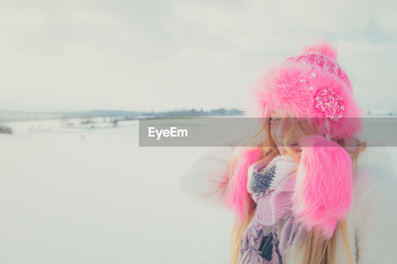 Woman with pink hat against sky during winter