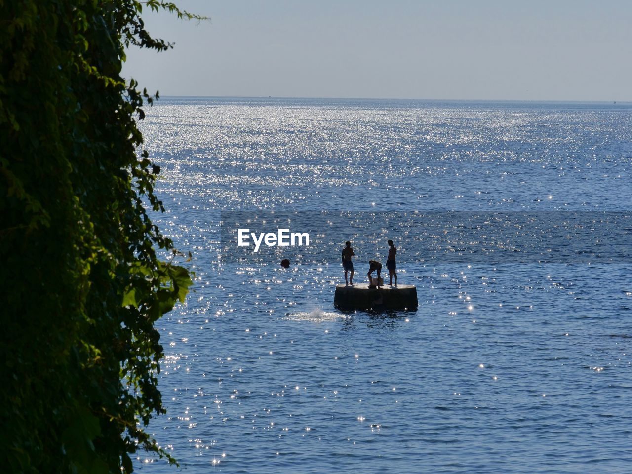 GROUP OF PEOPLE ON SEA AGAINST CLEAR SKY