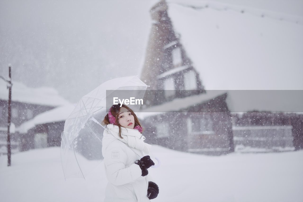 Woman with umbrella standing on field during winter