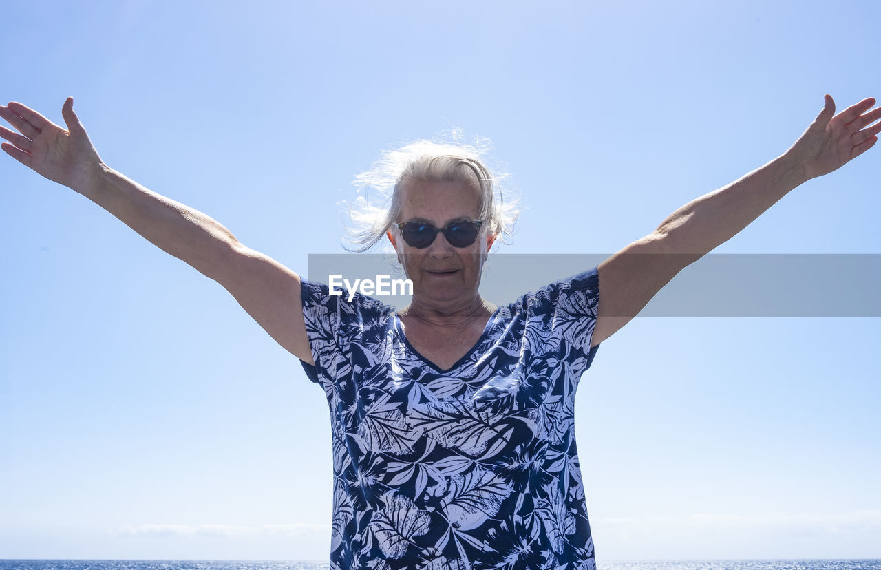 Portrait of woman wearing sunglasses standing against clear sky