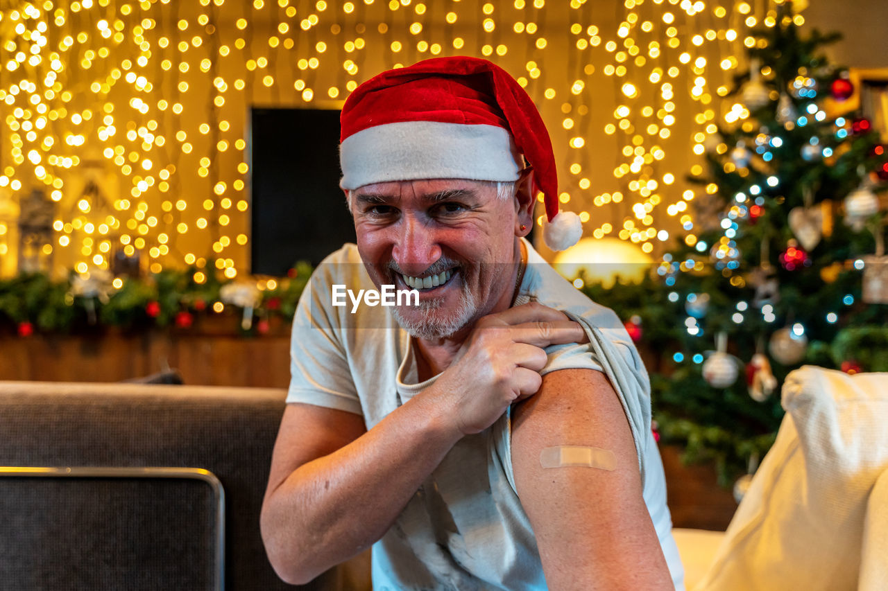 Portrait of a mature male smiling after getting a vaccine - man showing her arm with plaster