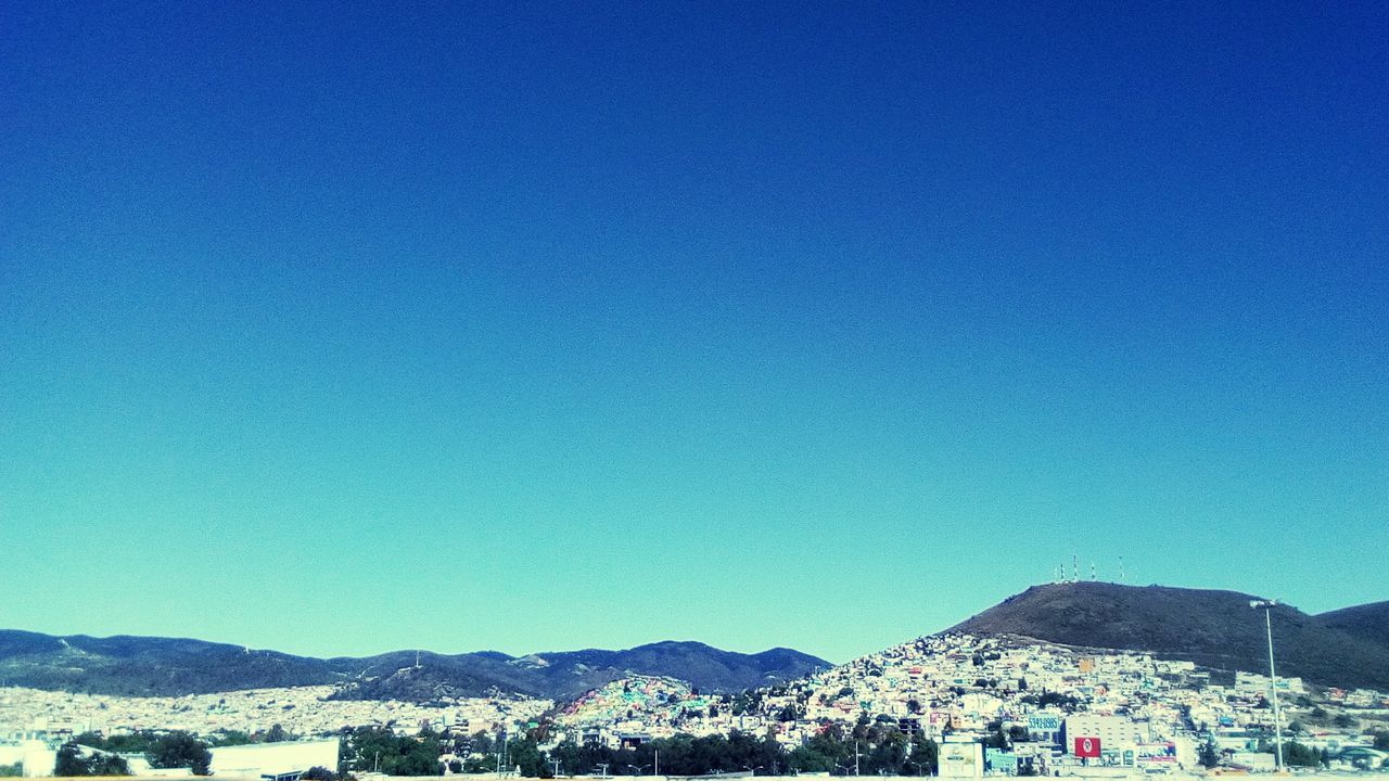TOWN BY MOUNTAIN AGAINST CLEAR BLUE SKY