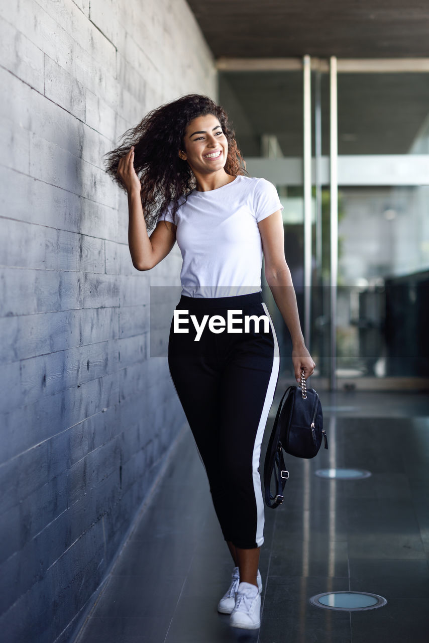 Portrait of smiling woman standing against wall