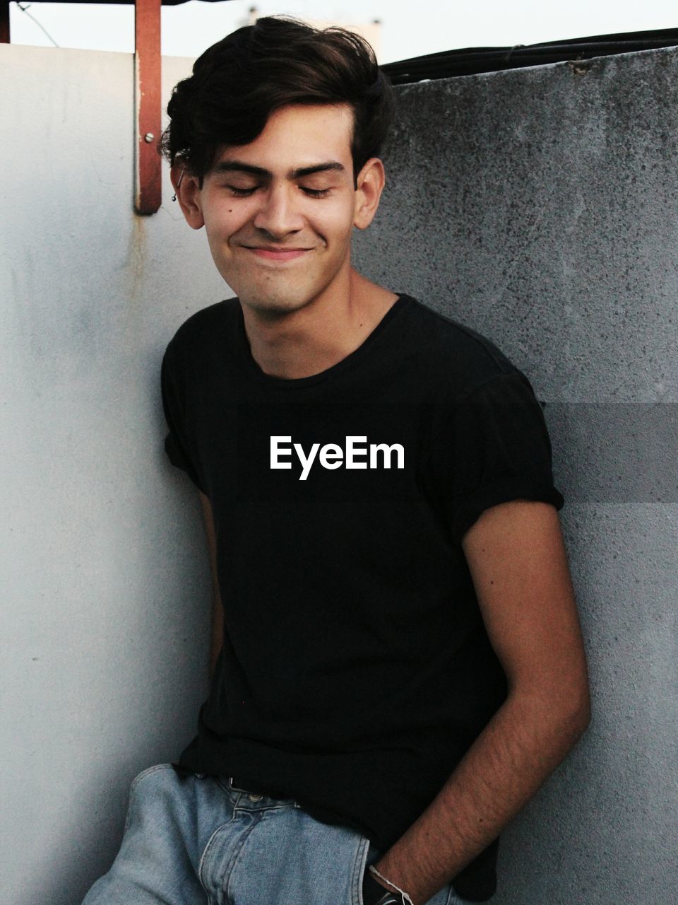 Portrait of smiling young man leaning against wall