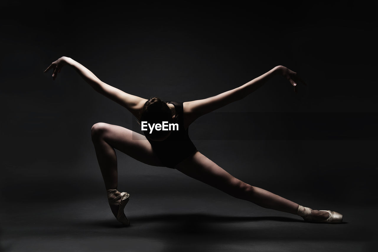 Ballet dancer dancing against gray background