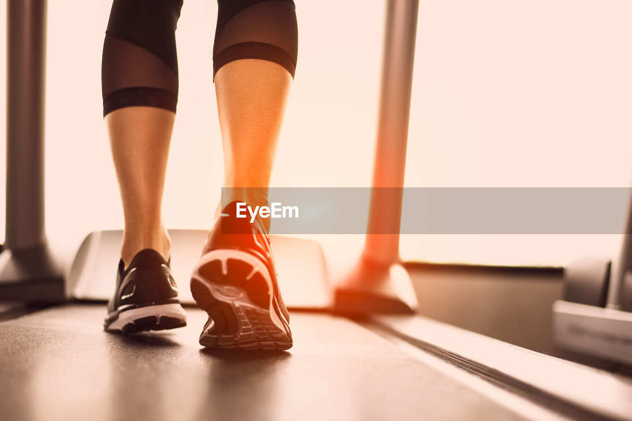 Low section of woman exercising on treadmill