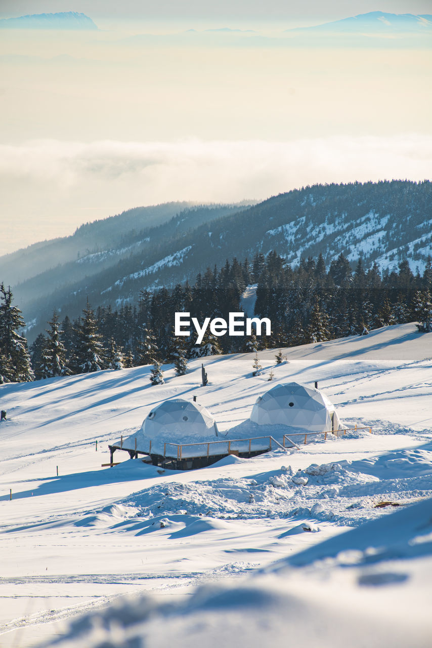 SNOW COVERED FIELD BY MOUNTAIN AGAINST SKY