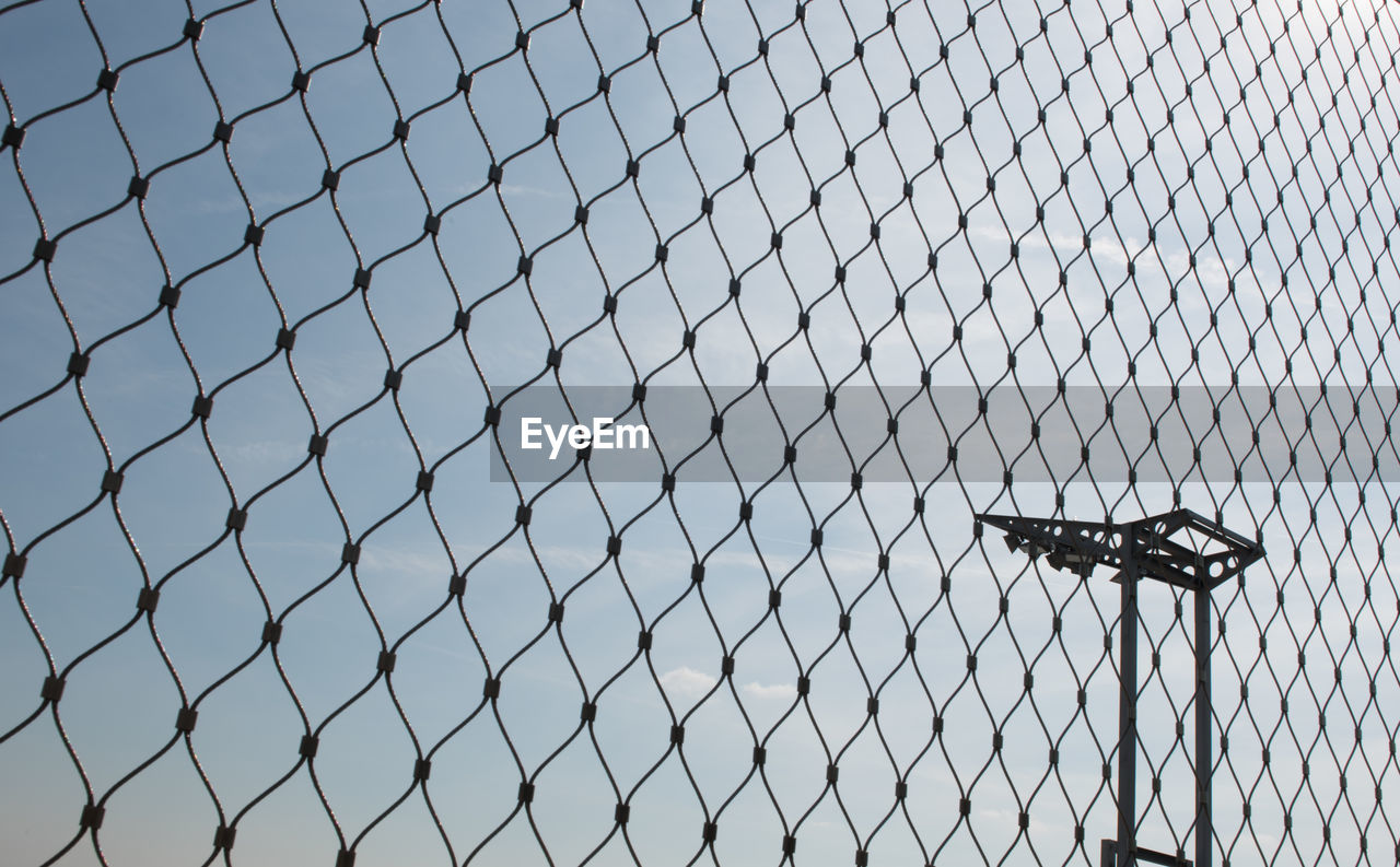 LOW ANGLE VIEW OF CHAINLINK FENCE AGAINST CLEAR SKY IN CITY