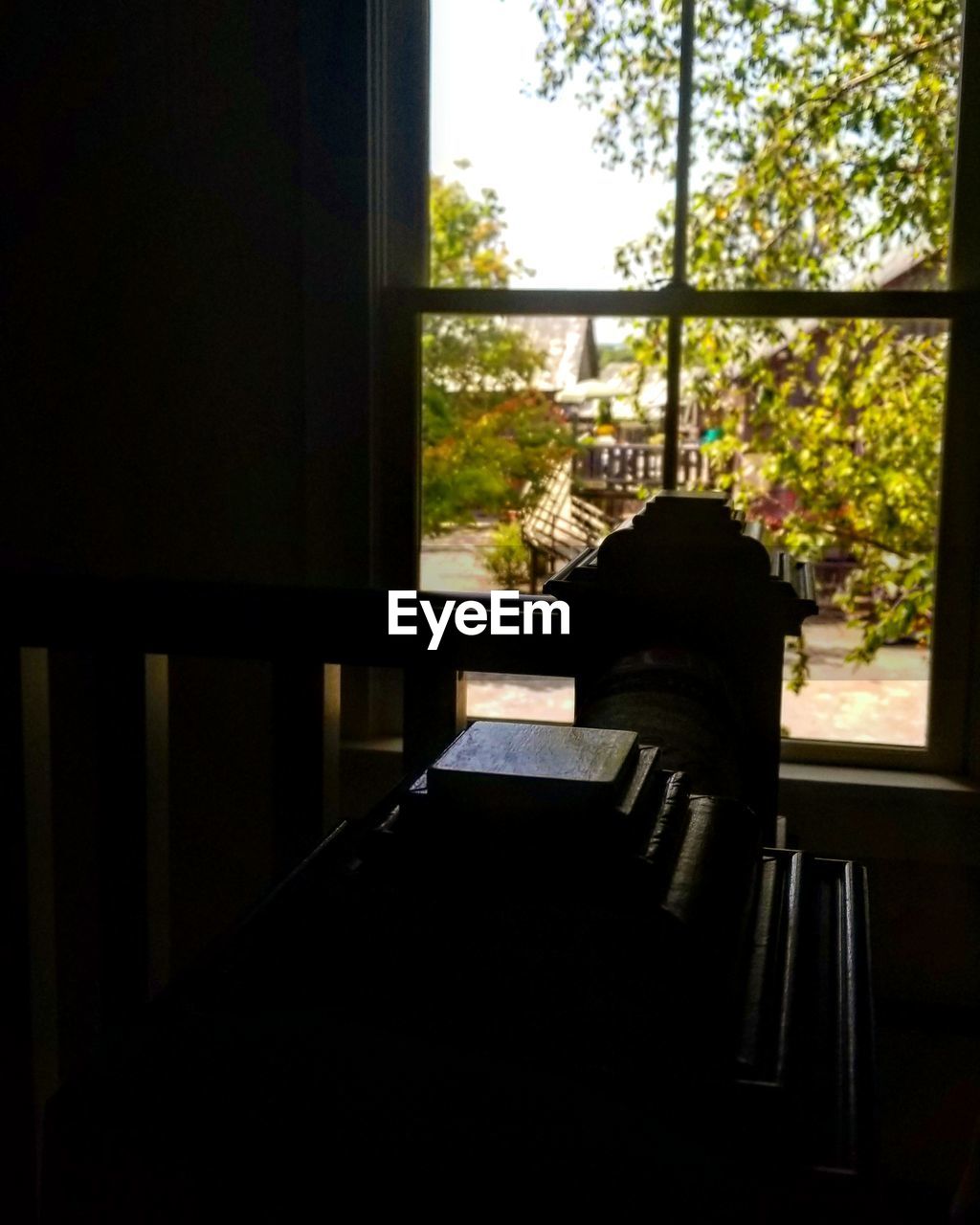 REAR VIEW OF MAN SITTING BY WINDOW