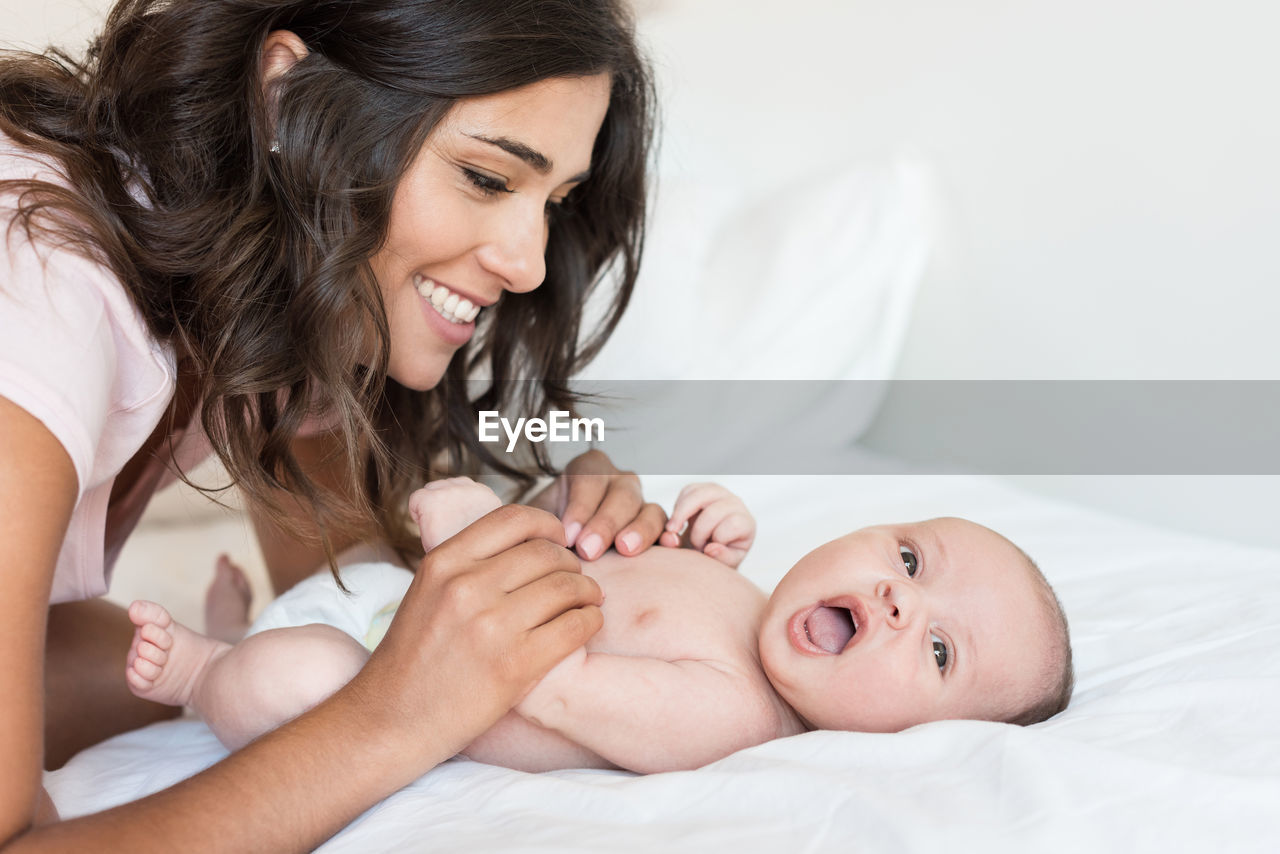 Close-up of mother playing with son on bed at home