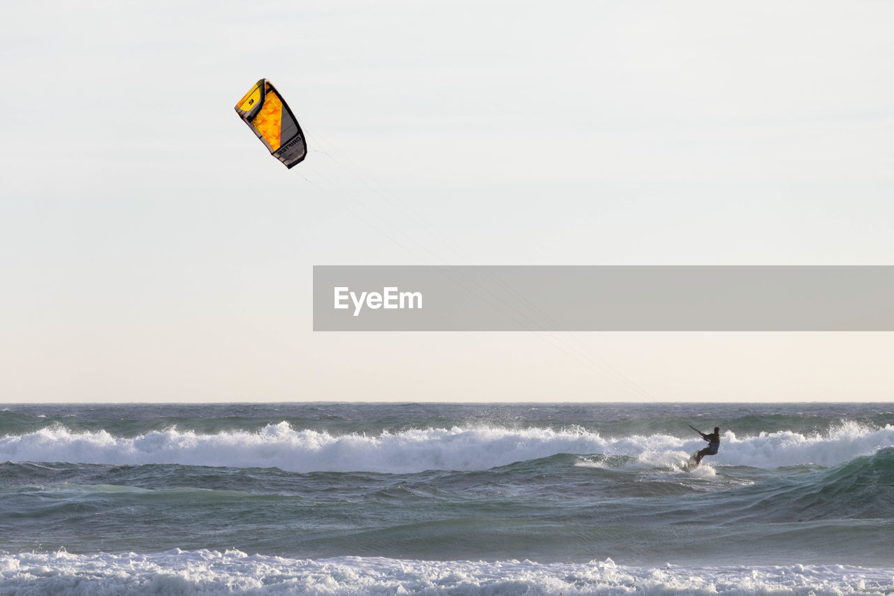 Mid distance view of silhouette person kitesurfing on sea