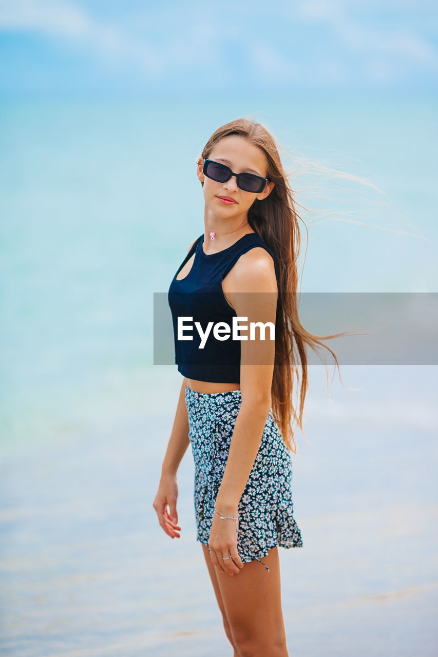 portrait of young woman wearing sunglasses standing against sky