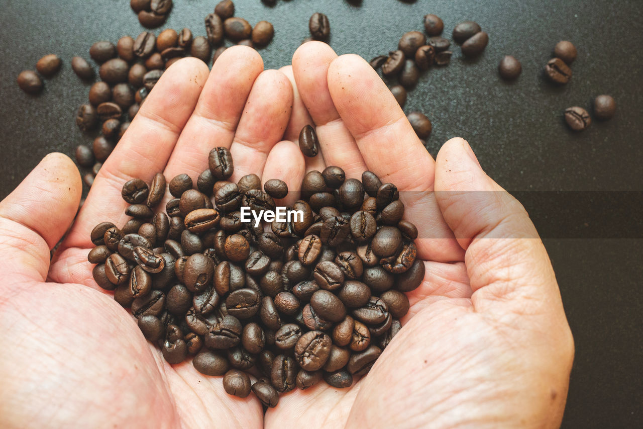 CROPPED IMAGE OF HAND HOLDING COFFEE BEANS