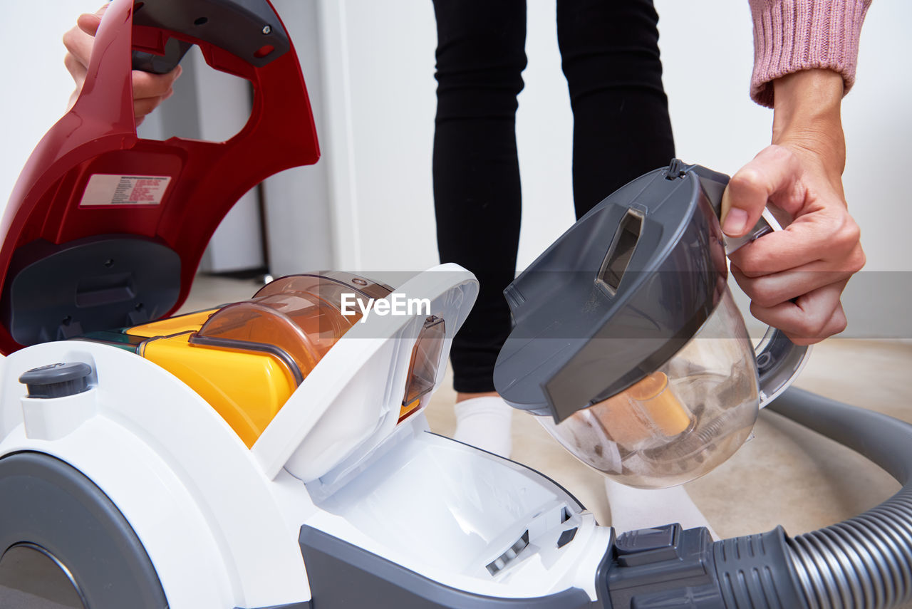 Woman takes out container of dust from vacuum cleaner