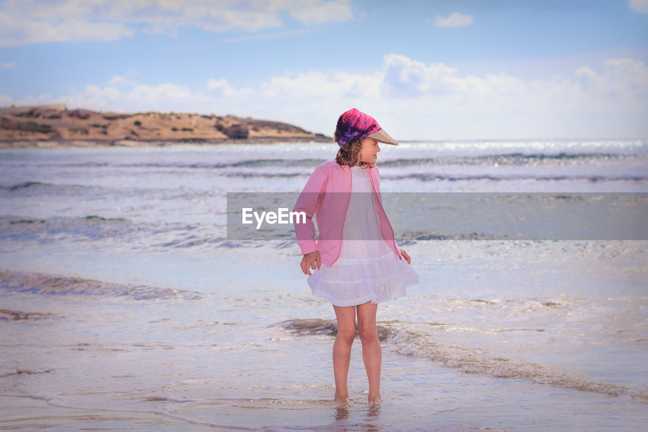 Girl standing in sea against sky