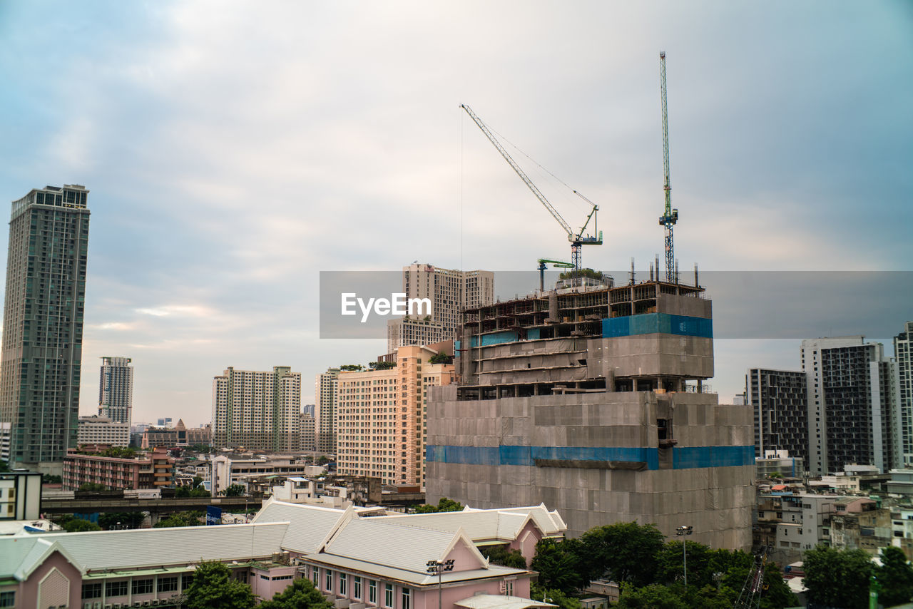 CRANES AND BUILDINGS AGAINST SKY