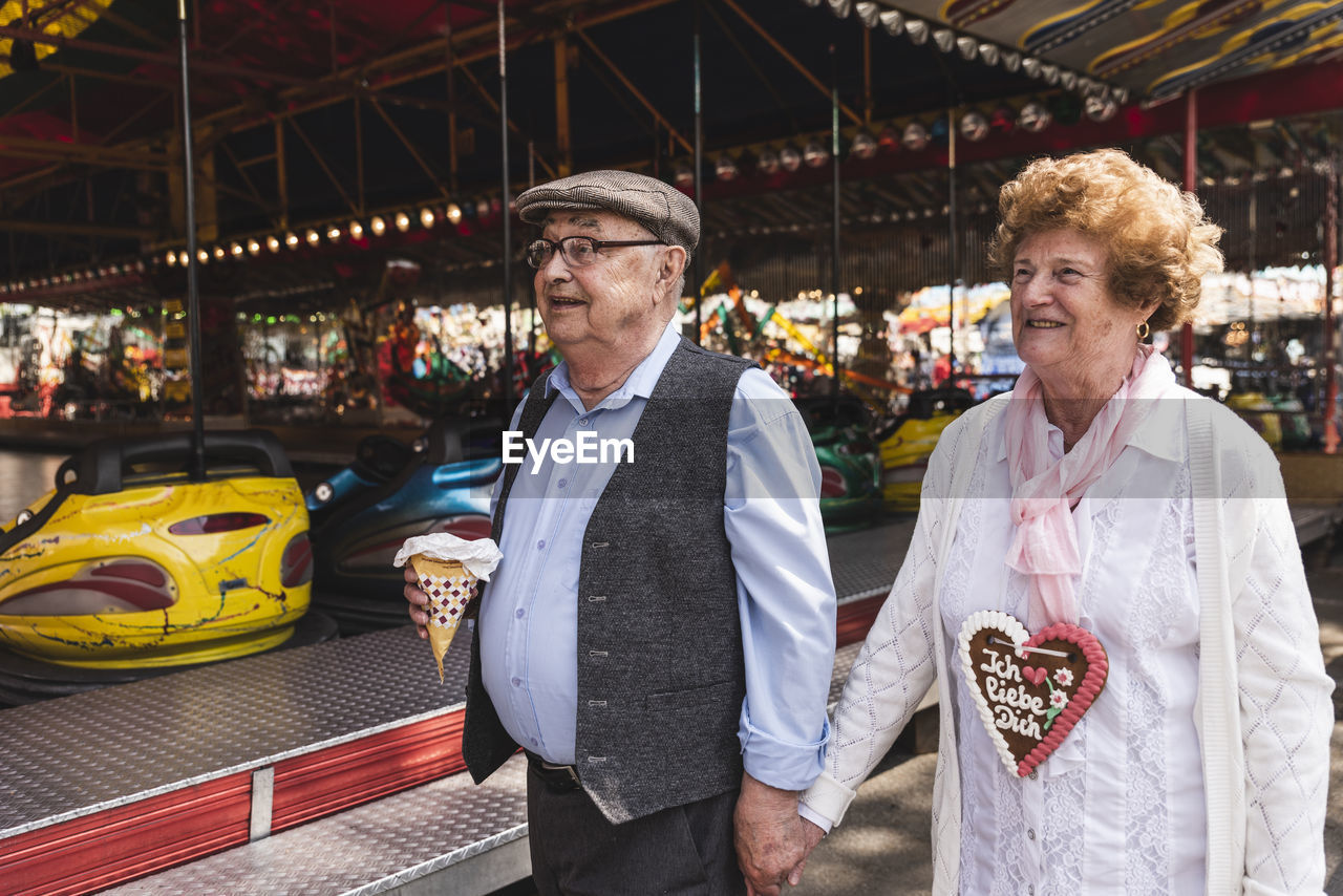 Happy senior couple walking hand in hand on fair