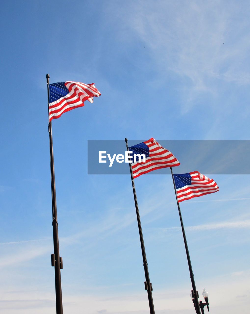 Low angle view of american flags against blue sky