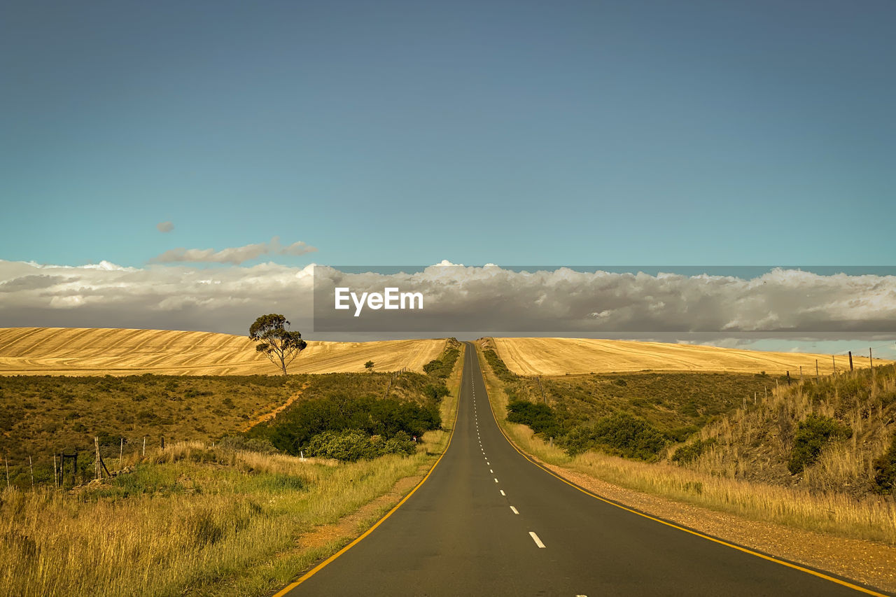 Empty road along landscape against sky