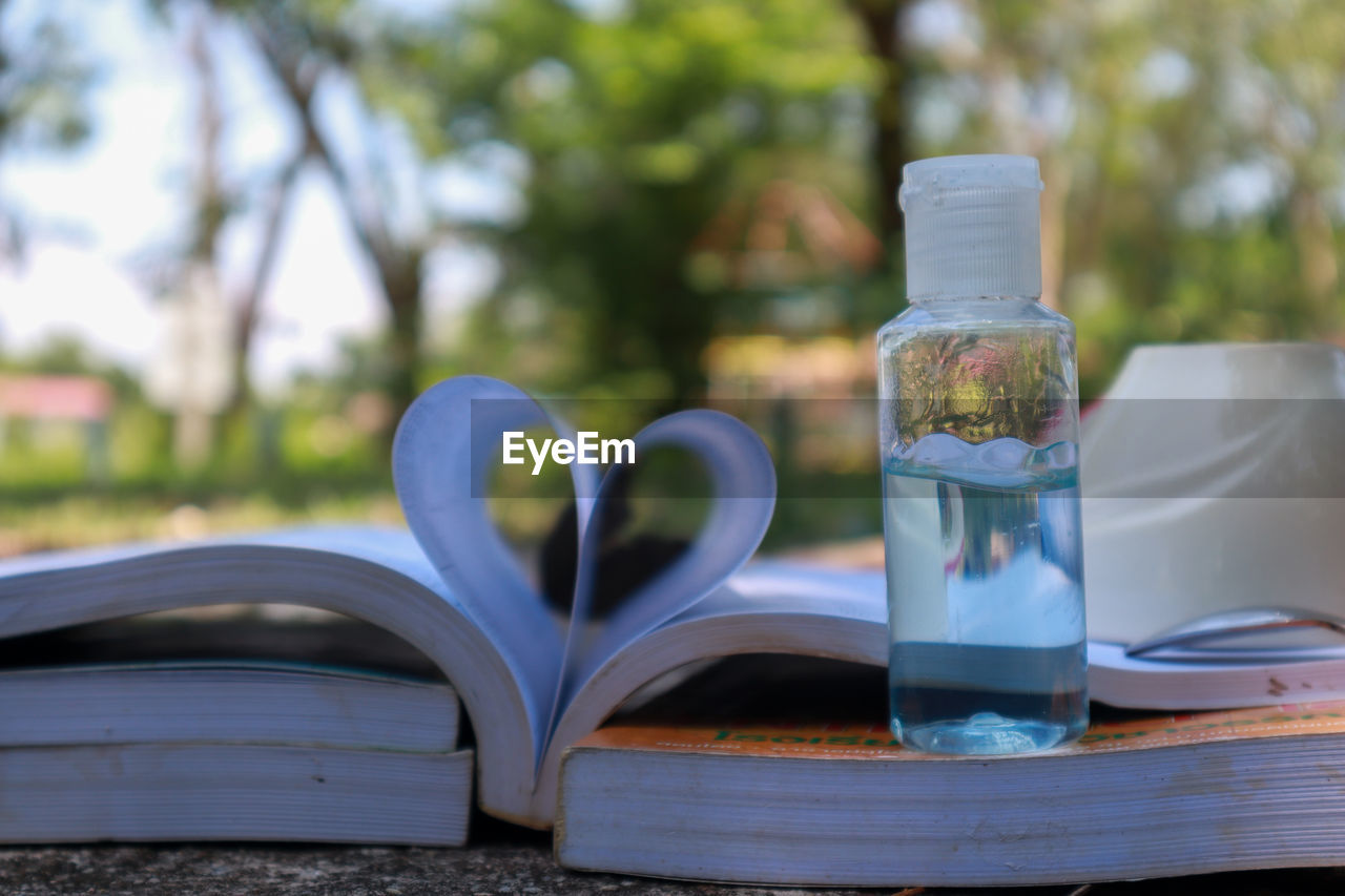 CLOSE-UP OF OPEN BOOK ON TABLE AGAINST GLASS