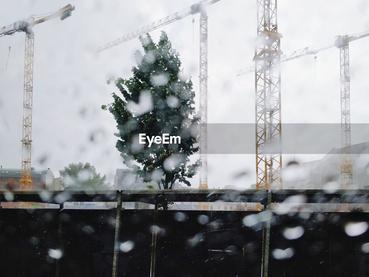 View through window wet glass onto construction site on rainy summer day