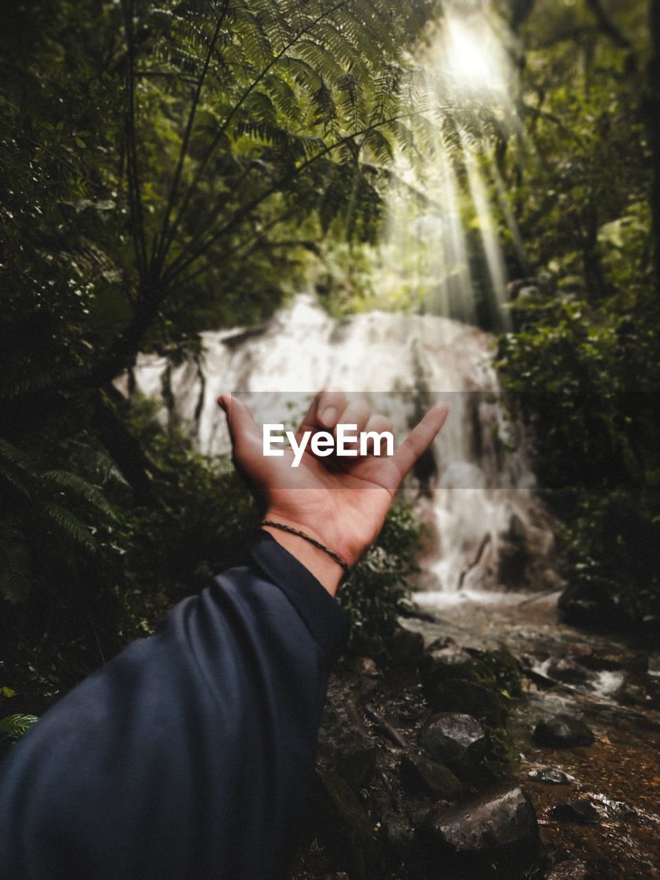 Midsection of person in waterfall at forest