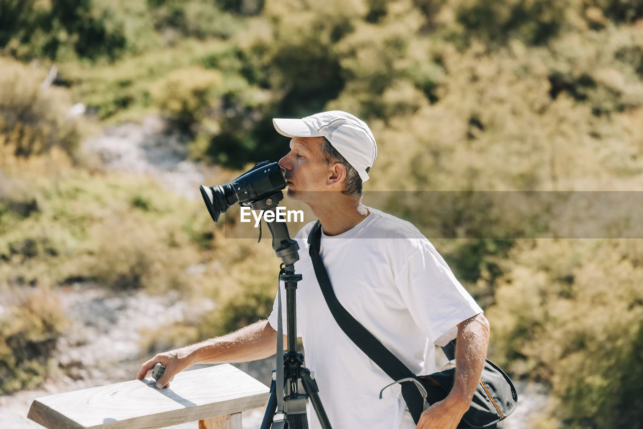 MAN PHOTOGRAPHING WITH CAMERA WHILE STANDING ON FARM