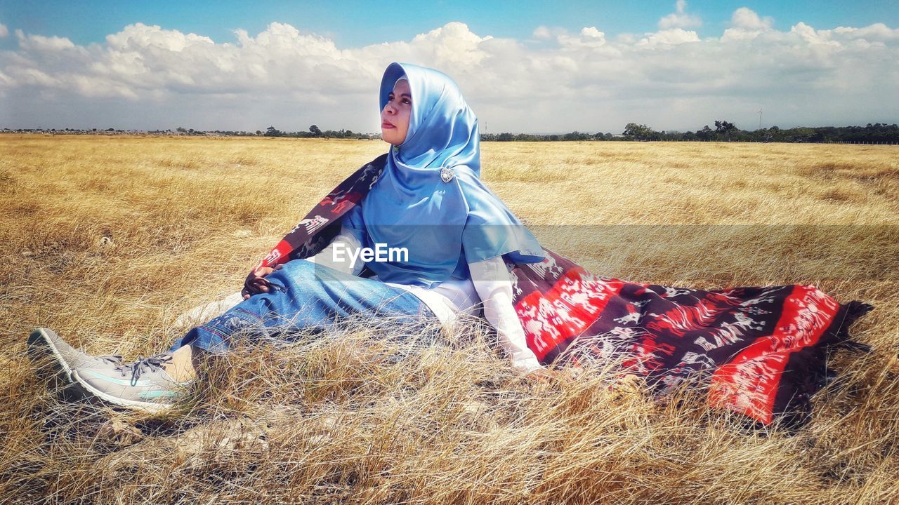 Rear view of woman sitting on field