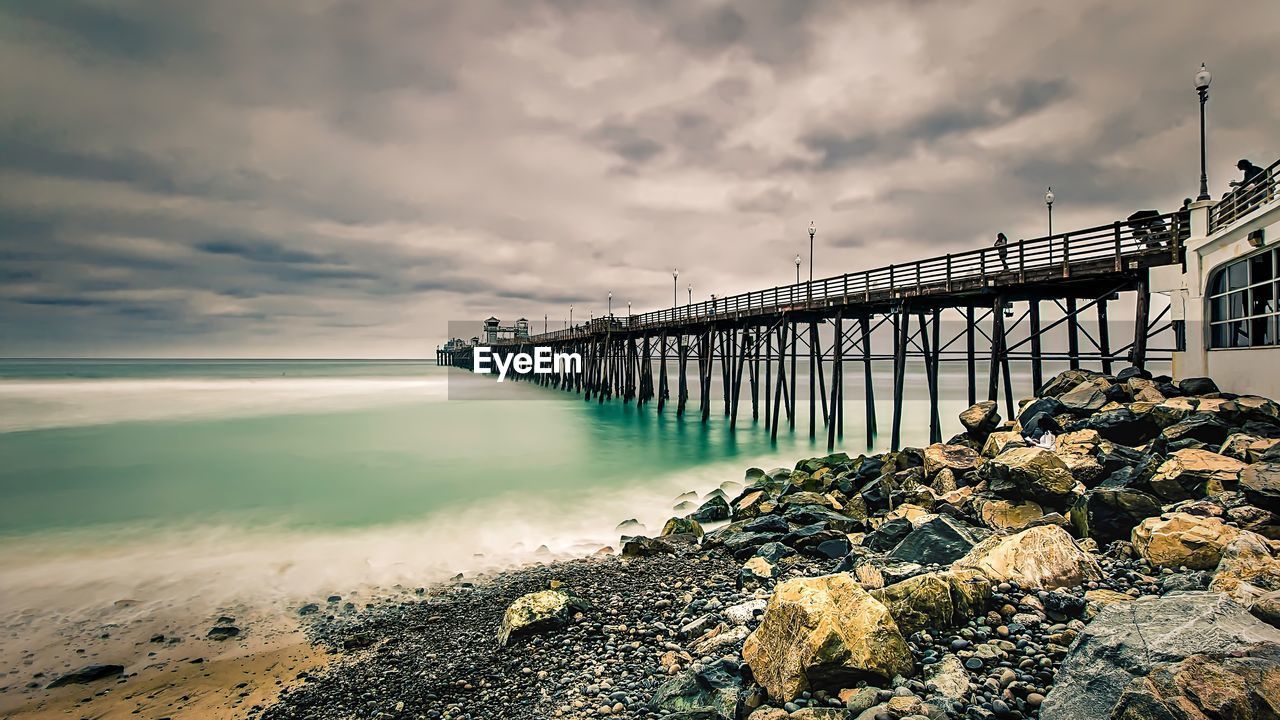 Pier at ocean against dramatic sky