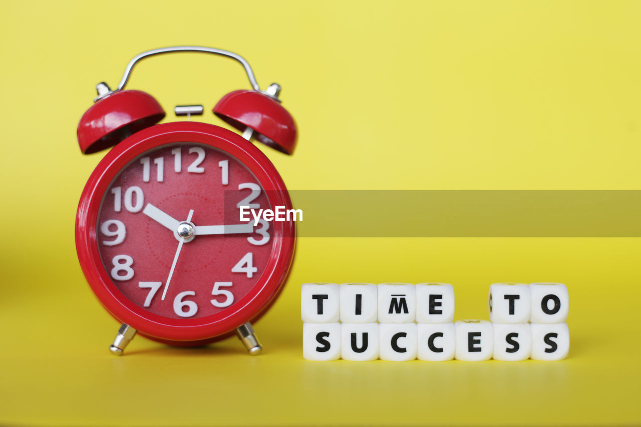 Time to success conceptual with word block and clock on yellow background