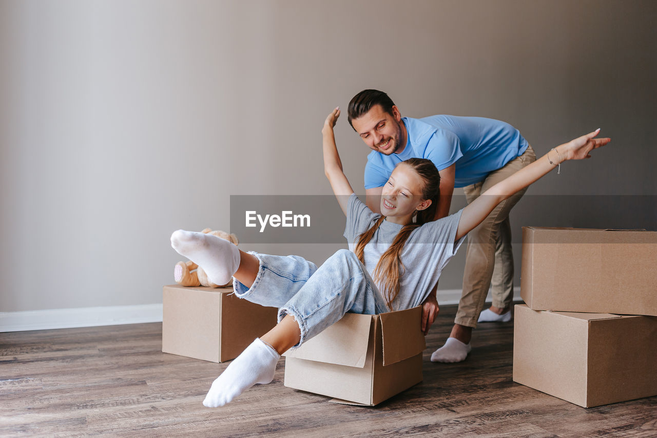 side view of young woman sitting on suitcase at home