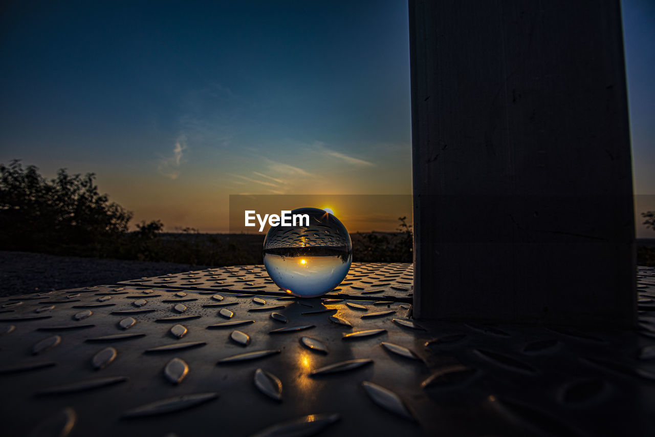 CLOSE-UP OF CRYSTAL BALL AGAINST SKY DURING SUNSET