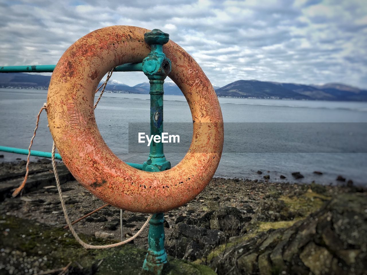 Old inflatable ring on railing at riverbank