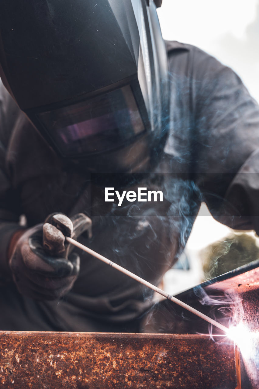 CLOSE-UP OF MAN WORKING ON BARBECUE