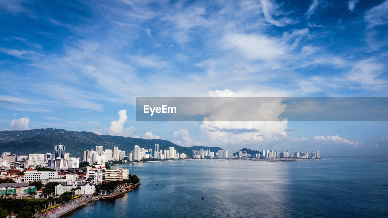 Panoramic view of bay and buildings against sky