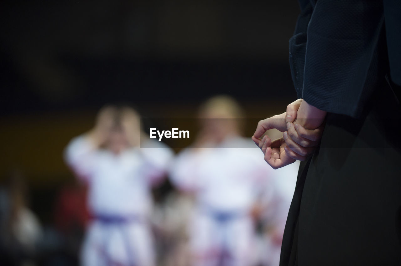 Midsection of person with hands behind back standing in stadium