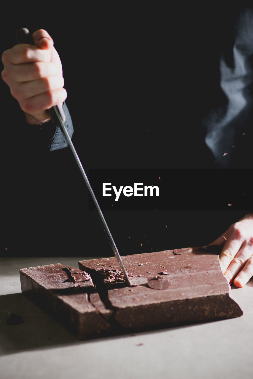 Cropped view of chef cutting chocolate