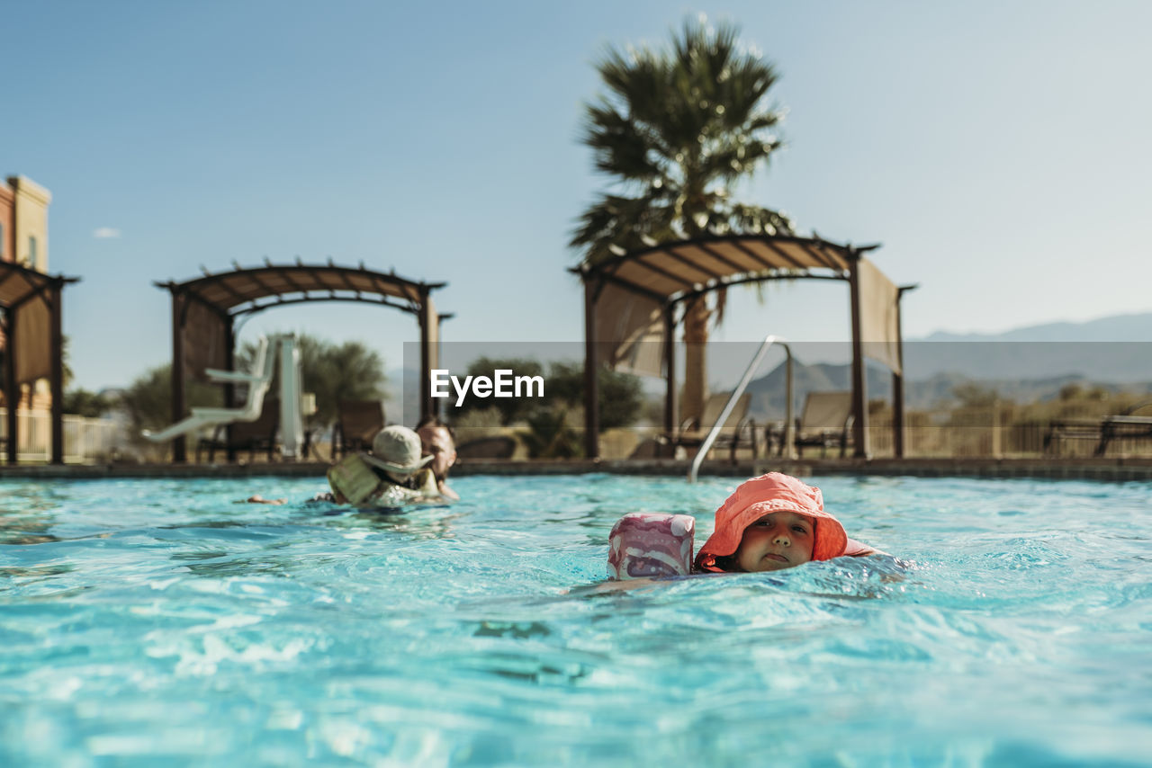 Young preschool age girl swimming in pool on vacation in palm springs