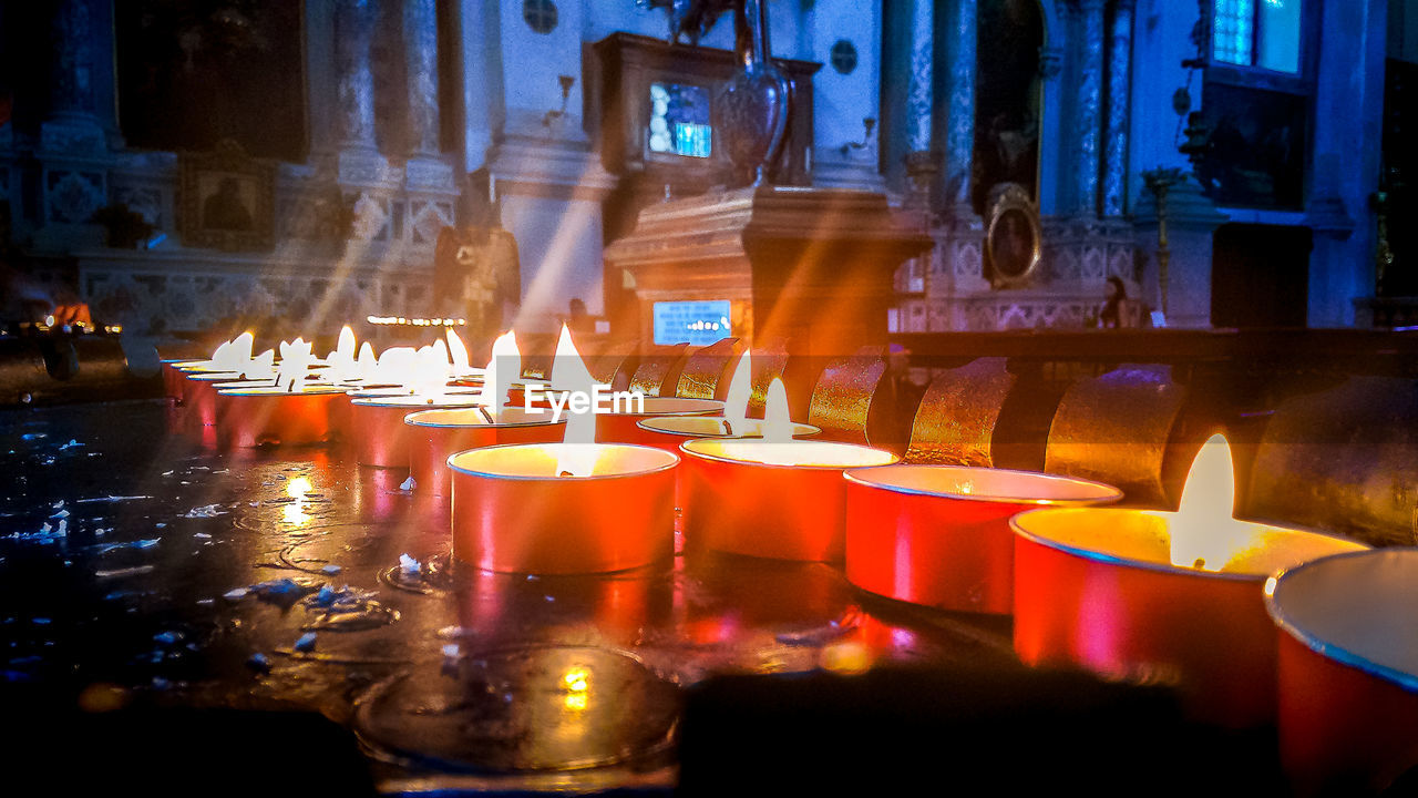 Close-up of illuminated tea lights on table in church