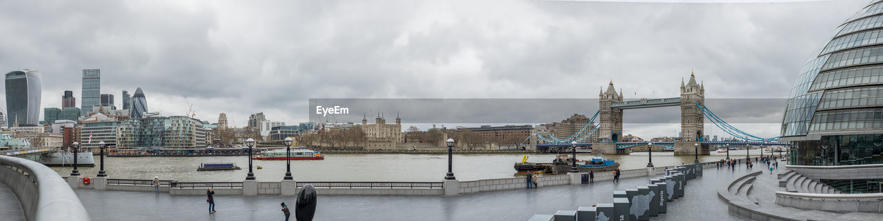 Panoramic view of thames river in city against cloudy sky