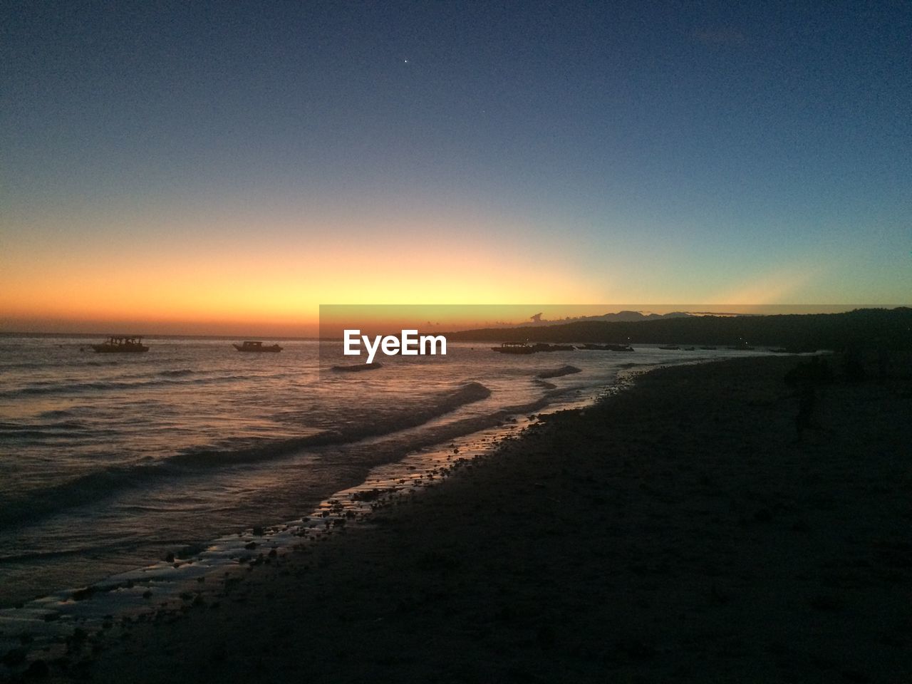 SCENIC VIEW OF BEACH AGAINST CLEAR SKY AT SUNSET