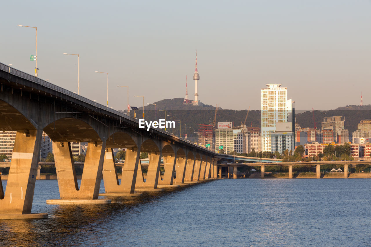 Bridge over river in city against clear sky